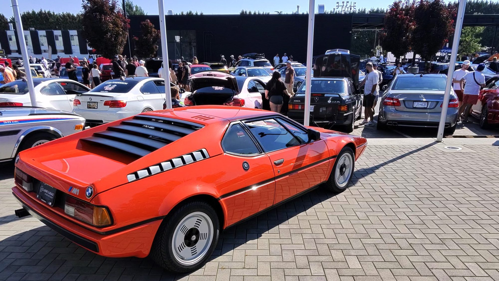 Orange BMW M1 among the cars at a Sunday cars and coffee meet